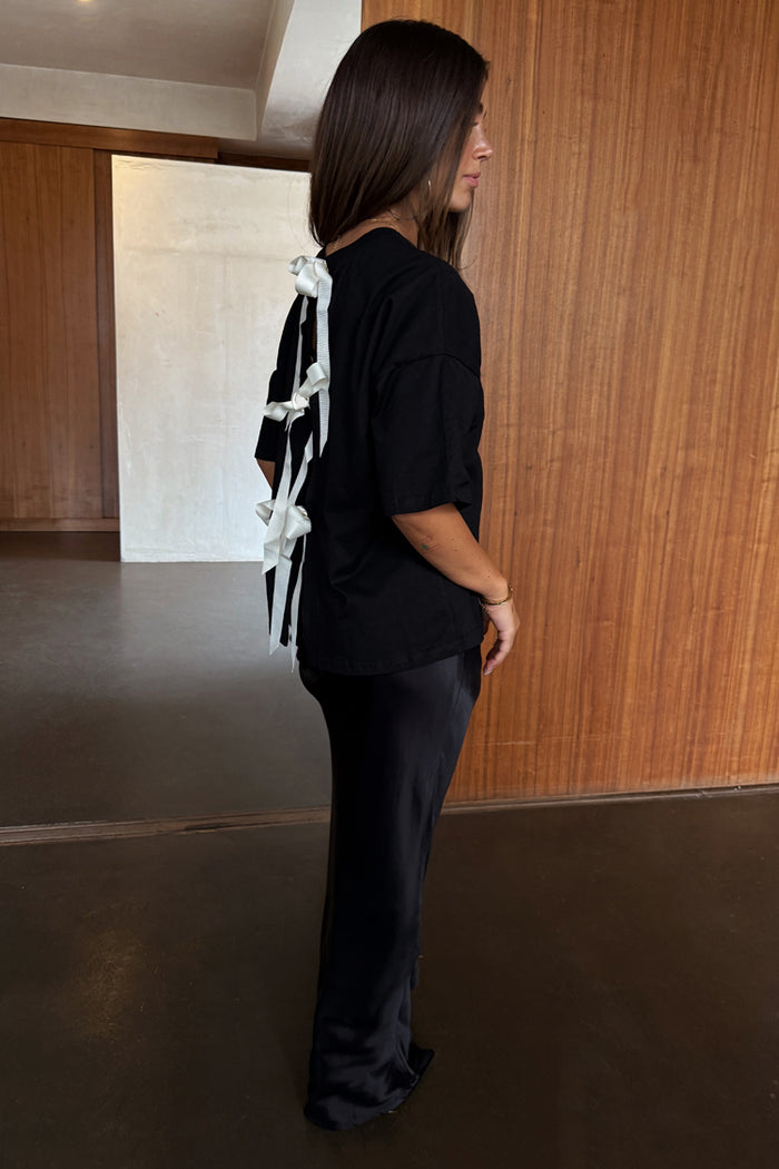 Black Bow Back T-Shirt featuring cream ribbon fastenings and dropped shoulders, styled with a black satin skirt.