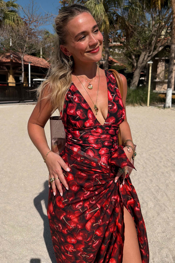 Black Cherry Sarong with a deep red cherry print, tied over a matching swimsuit for a beach vacation look.