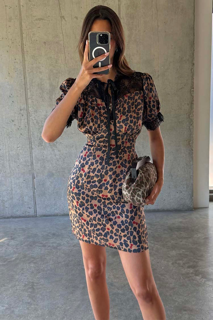 Cherry Leopard Mini Lyla Dress featuring black lace trim, tie neck and cherry print, shown in a mirror selfie.