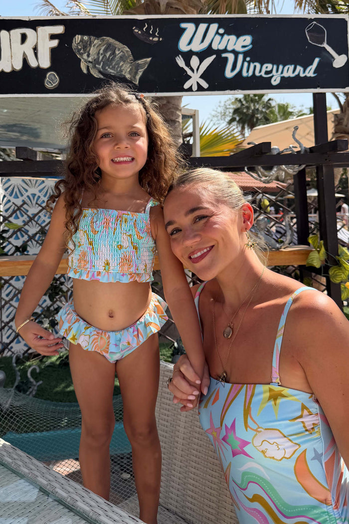 Blue NFD Kids Starburst smocked bikini set with frill trims, paired with a matching adult swimsuit on vacation.