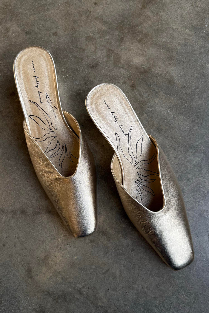 Metallic Gold Wedge Mules with a pointed toe and sculpted heel, featuring a signature graphic on the inner sole.