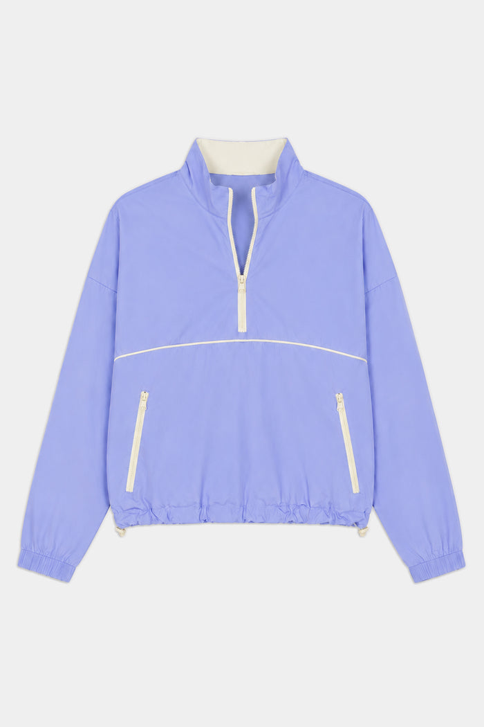 The SPLITS59 Lyle Woven Nylon Pullover in Purple Haze/Creme features a soft nylon-spandex blend, white zipper accents, high collar, elastic cuffs and hem, and two front zippered pockets.