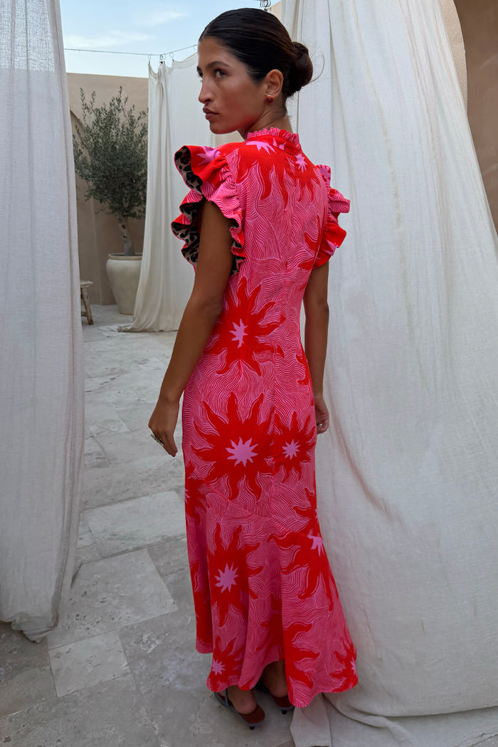 Pink Soleil Remi Dress with red sun motifs, pleated frill sleeves with leopard lining and an asymmetrical skirt.
