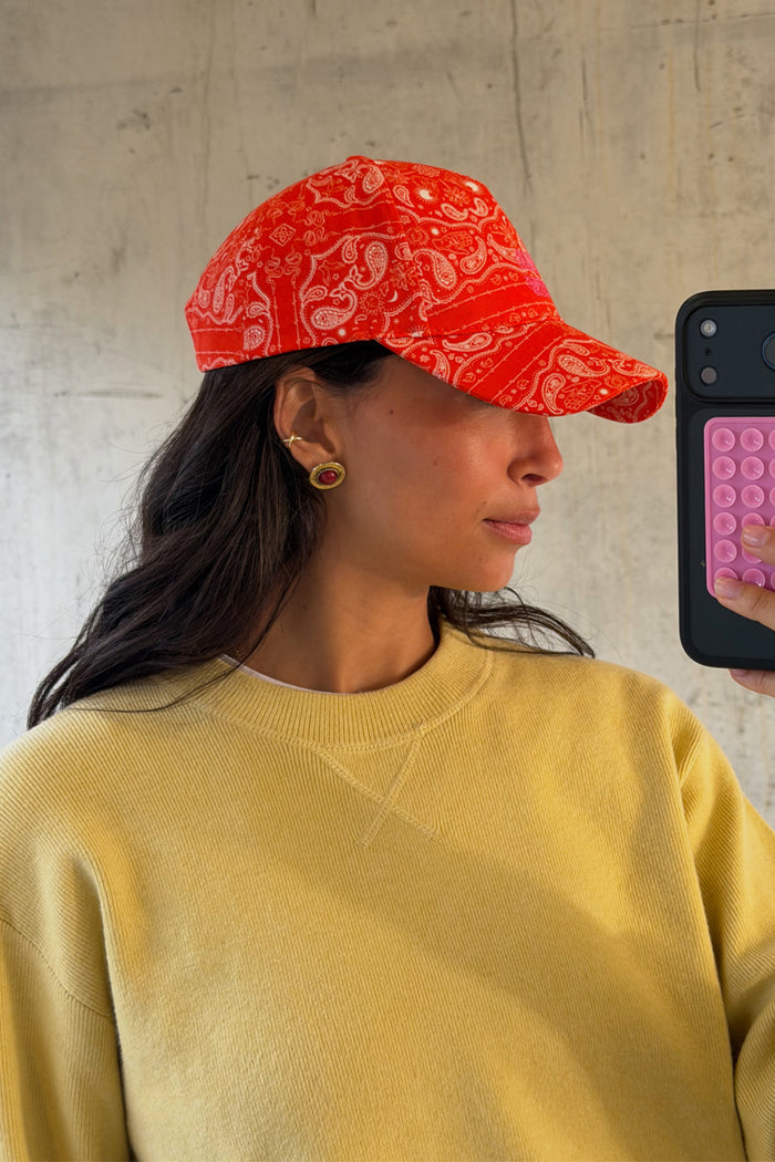 Red Bandana Cap in a white paisley print, styled with a yellow sweatshirt in a casual mirror selfie.