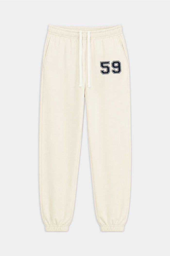 The Serena French Terry Oversized Sweatpant by SPLITS59 in Creme/59 is crafted from soft 100% cotton, featuring an elastic waistband, drawstring, cuffed ankles, and a black and white “59” detail on the left thigh.