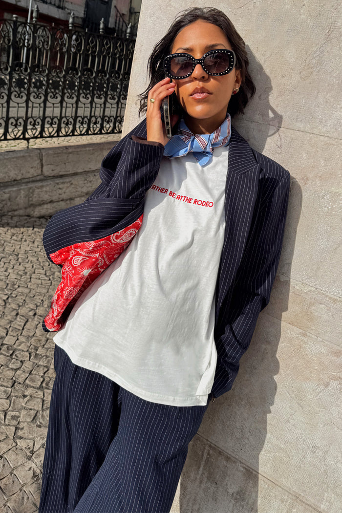 White Rodeo T-Shirt with red text, styled with a pinstripe suit and blue neck scarf for a London look.
