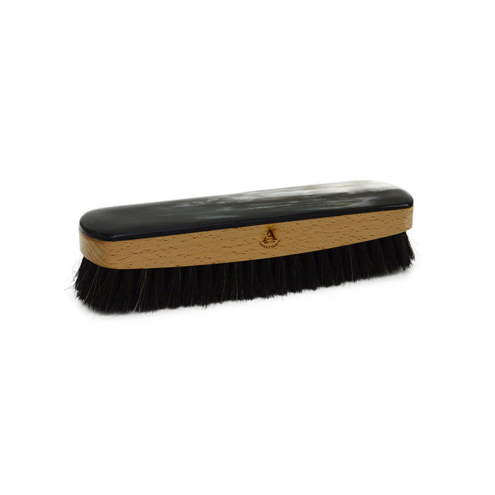 A handcrafted shoe polishing brush with a black and white oxhorn handle and dark bristles, presented on a plain background.