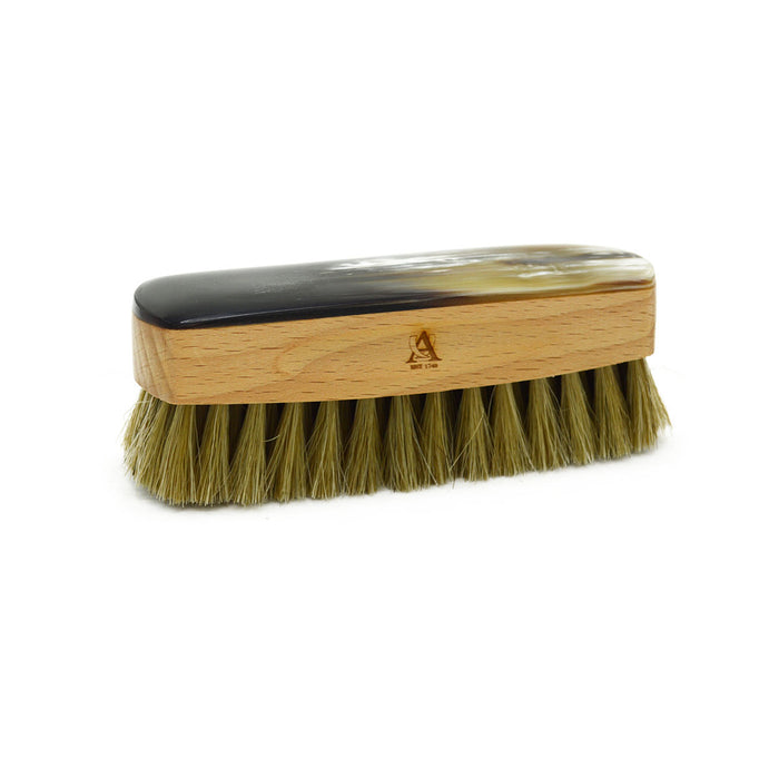 A handcrafted shoe polishing brush with a black and white oxhorn handle and dark bristles, presented on a plain background.