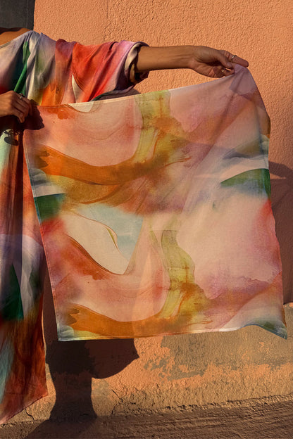 Abstract Scarf in a colourful multi-tonal print, held up to show the soft-touch fabric and square bandana style.