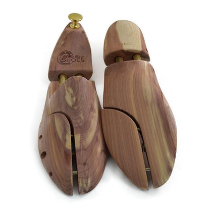A pair of uncompressed cedar wood shoe trees with brass fitments, displayed in an open position.