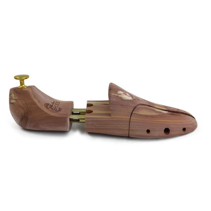 A pair of uncompressed cedar wood shoe trees with brass fitments, displayed in an open position.