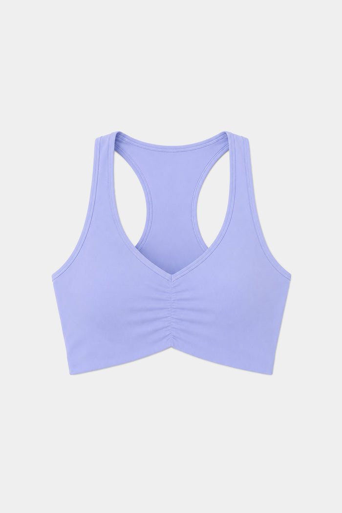 The SPLITS59 Airweight Bra with Ruching in Purple Haze features a racerback design and front ruching, crafted from a soft nylon-spandex blend, shown against a plain white background.