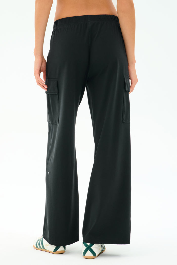A person wearing SPLITS59 Alex Airweight Cargo Pant in black and white sneakers with green stripes, photographed from the back. Ideal for a post-workout stroll or a casual day out.