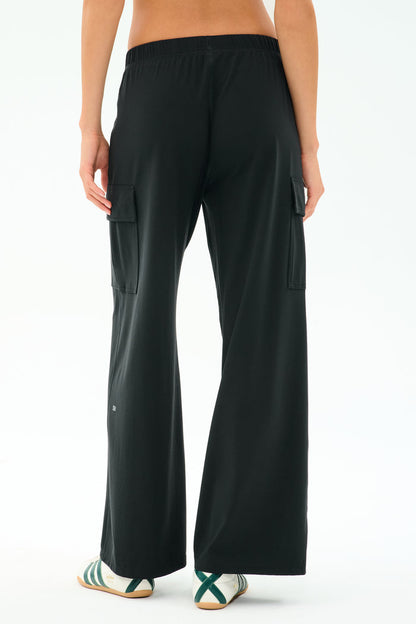 A person wearing SPLITS59 Alex Airweight Cargo Pant in black and white sneakers with green stripes, photographed from the back. Ideal for a post-workout stroll or a casual day out.