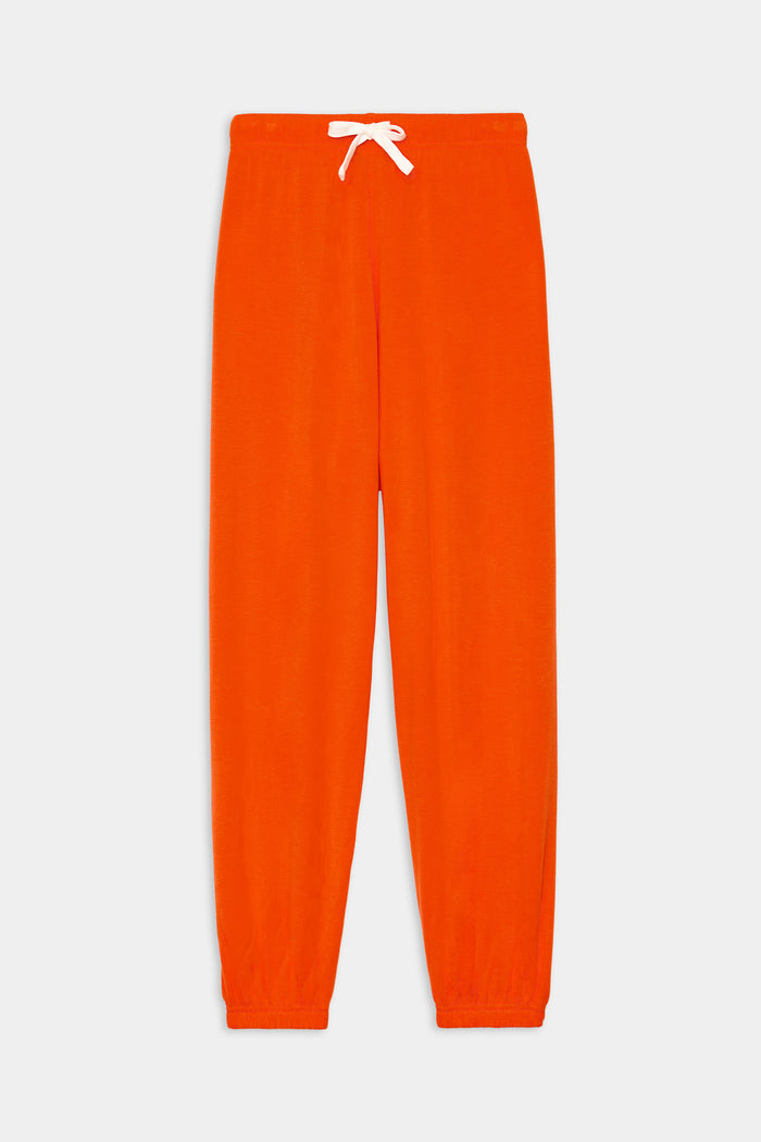 The SPLITS59 Andie Oversized Fleece Sweatpant in Valencia features bright orange fleece, an elastic waistband, white drawstring, and elastic cuffs, shown laid flat on a white background.