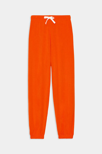 The SPLITS59 Andie Oversized Fleece Sweatpant in Valencia features bright orange fleece, an elastic waistband, white drawstring, and elastic cuffs, shown laid flat on a white background.