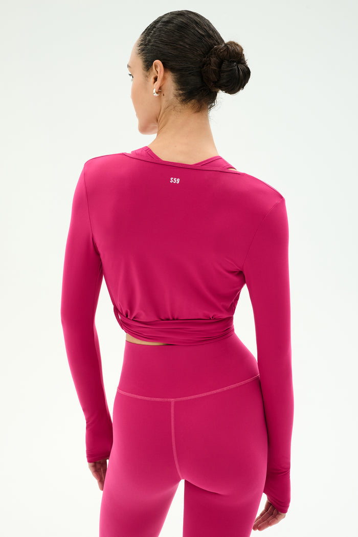 A woman with dark hair in a bun is shown from the back, wearing the SPLITS59 Bella Airweight Lite Wrap in Sangria against a plain light background.