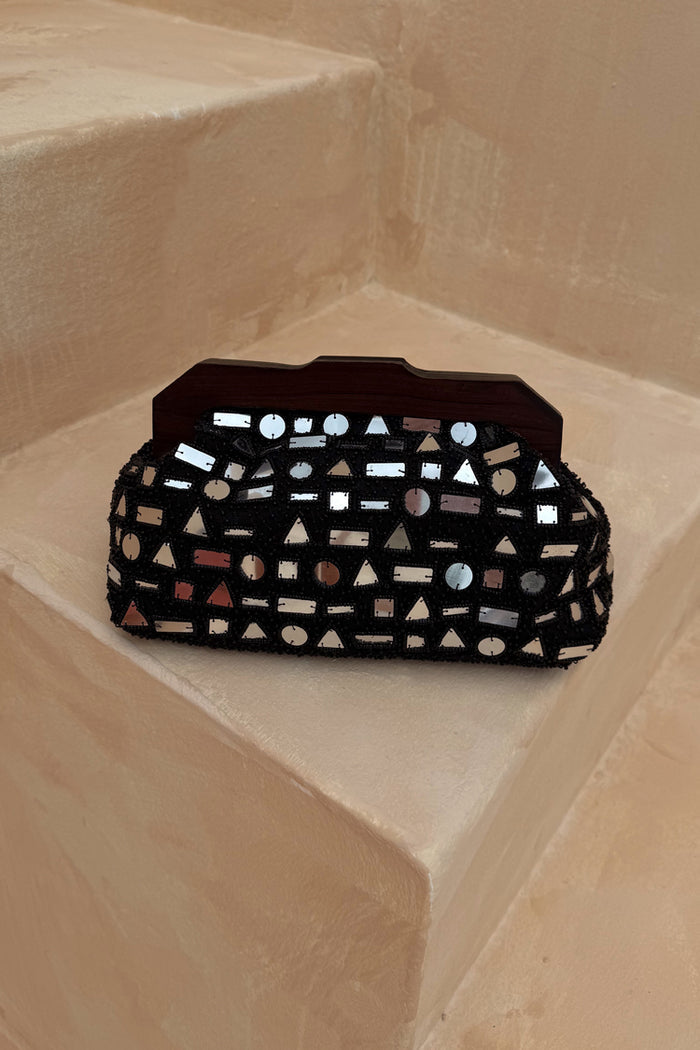 Black Beaded Mirror Bag featuring silver geometric glass beading and a wooden handle on a stone step.