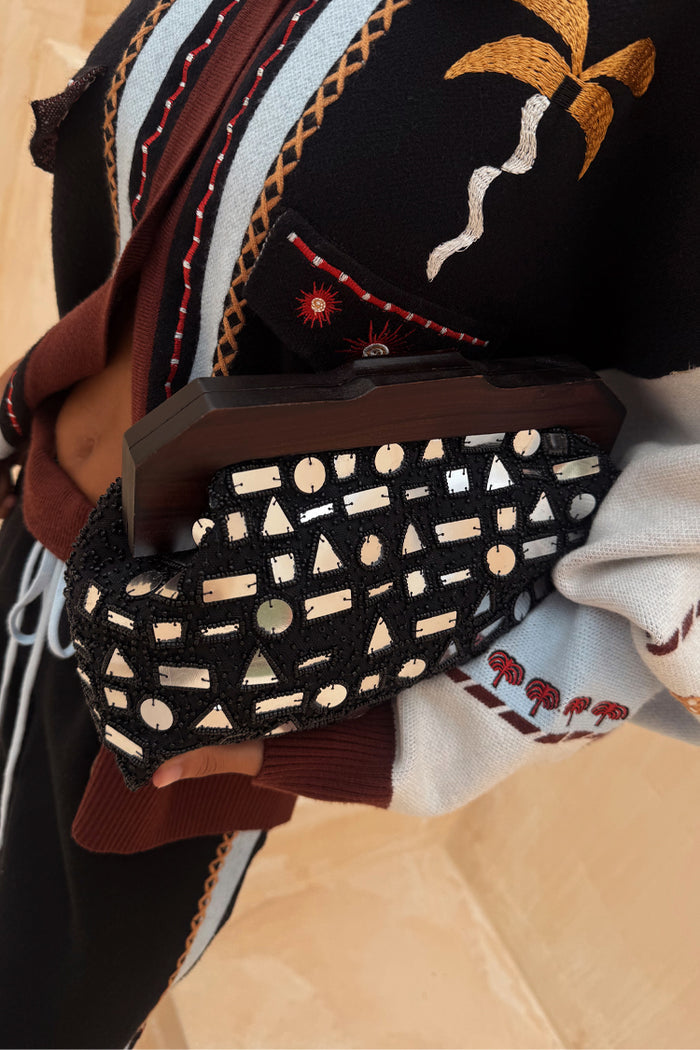 Black Beaded Mirror Bag with silver glass shapes and a wooden handle, held against a patterned cardigan.