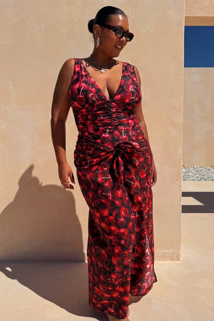 NFD Black Cherry Sarong with a red cherry print and tie-waist, styled with a matching swimsuit for vacation.