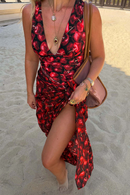 Black Cherry Sarong with a deep red cherry print and tie-waist fastening, styled on a sandy beach.