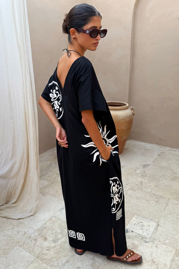 Black cotton Dolce Vita T-Shirt Dress with sun motifs and Greek graphics, showing the V-back and side pockets.