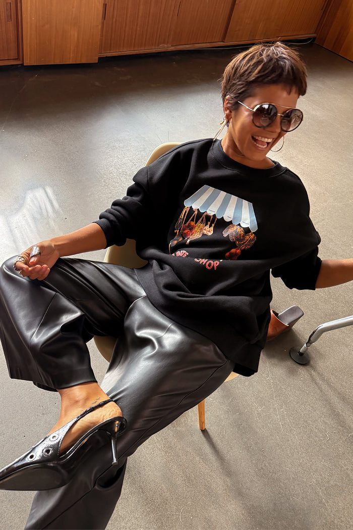Black Fruit Shop Sweatshirt with a graphic print, styled with black leather-look culottes and oversized sunglasses.