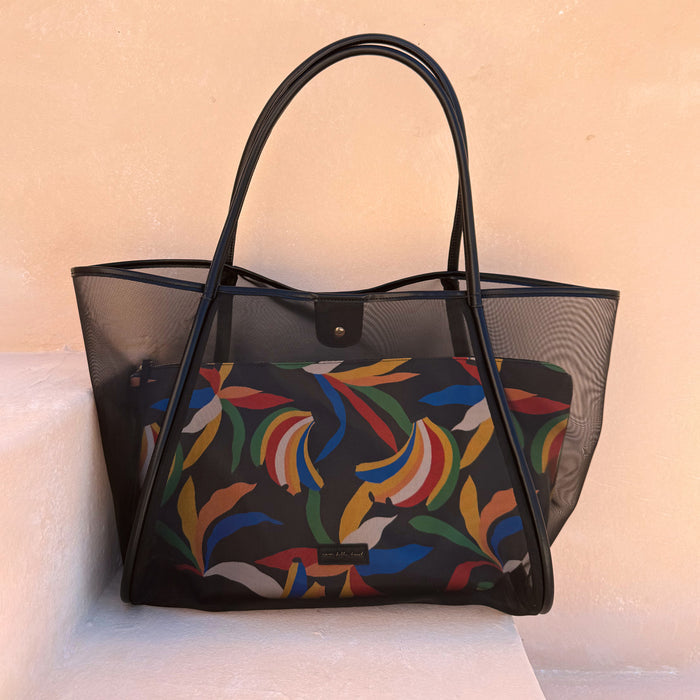 Black Mesh Tote Bag with a colourful banana print inner pouch and leather straps, styled on a stone step for vacation.