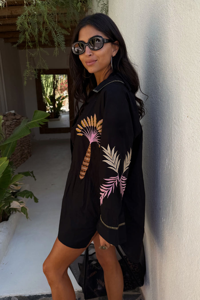 Black Palm Embroidered Shirt with pink and yellow palm motifs on the sleeves, styled in a vacation setting.
