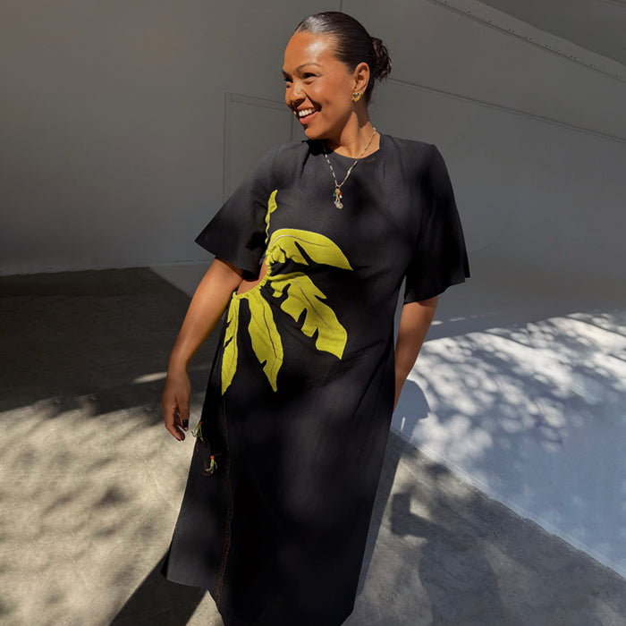 Black Palm Riviera Dress with a yellow palm leaf print and adjustable side cut-out detail.