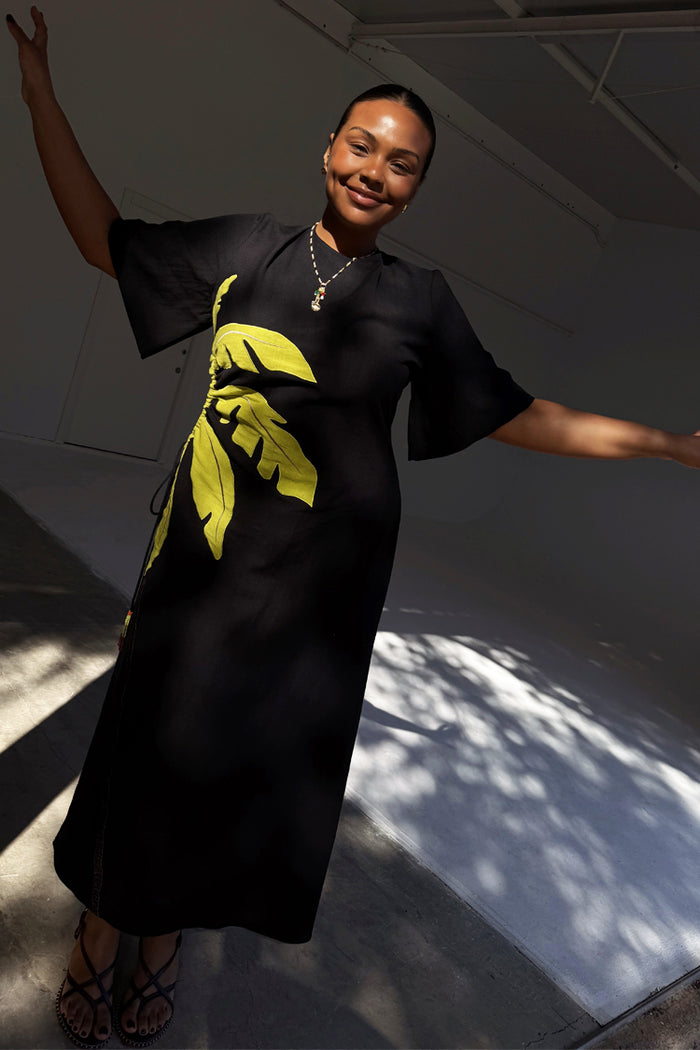 Black Palm Riviera maxi dress featuring a yellow palm motif and side waist cut-out detail.