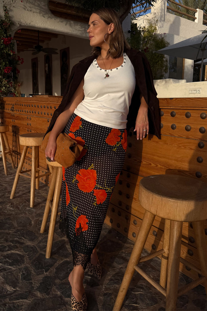 Black Poppy Midi Maeva Skirt with an iconic red floral print and lace trim, styled with a white tank and suede jacket.