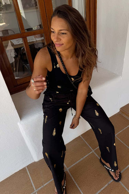 Black Shell Elissa Trousers Petite with a gold shell print and wide-leg fit, shown in a relaxed lifestyle setting.