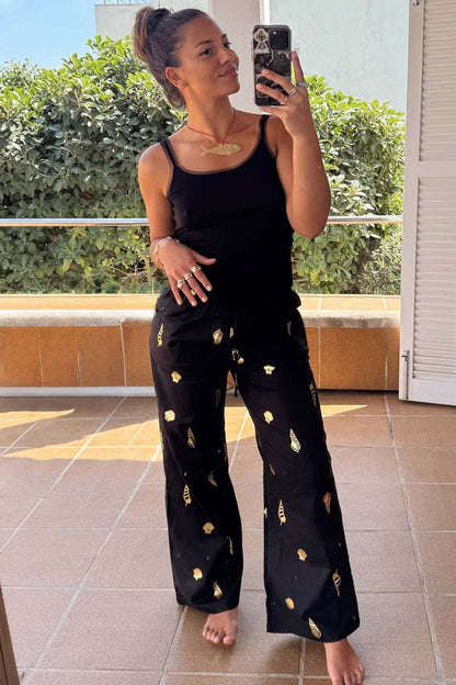 Black Shell Elissa Trousers with gold seashell motifs and a wide-leg fit, styled in a mirror selfie.