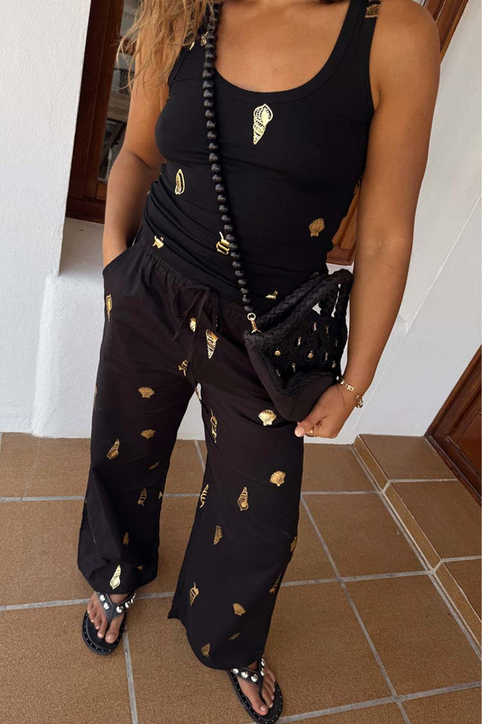 Black Shell Elissa Trousers with gold shell print, styled in a wide-leg vacation co-ord with matching top.
