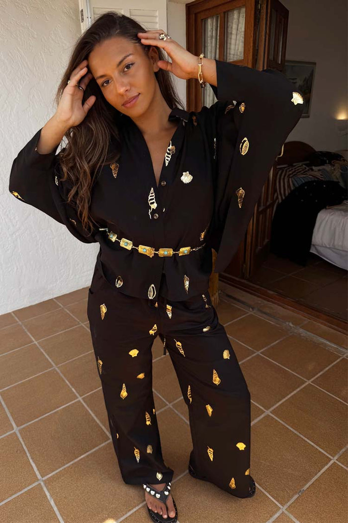 Black Shell Elissa Trousers in a cotton-linen blend with gold shell print, styled as a vacation co-ord.