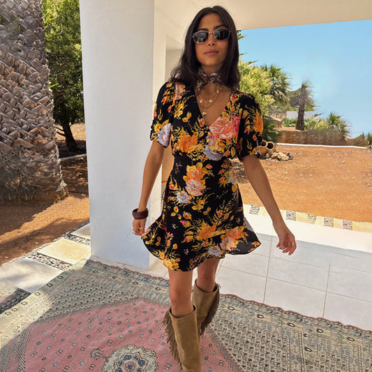 Black Sofia Mini Tea Dress with a floral print and frill hem, styled with tan fringe boots.