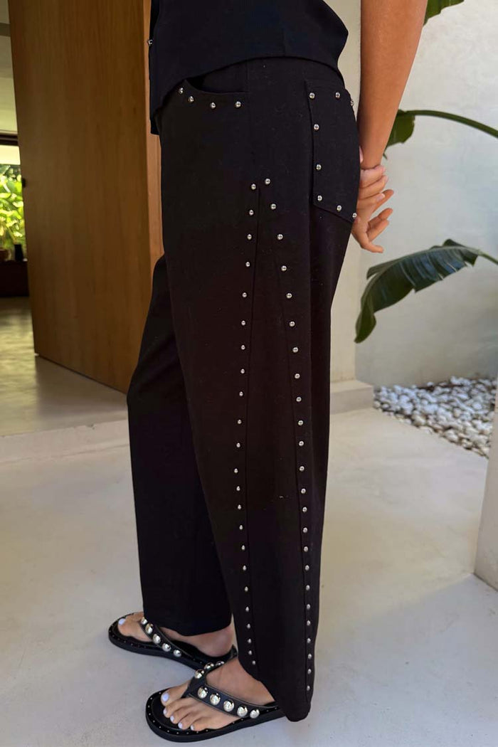 Black Studded Barrel Jeans featuring silver studs along the side and pockets, styled with studded sandals.