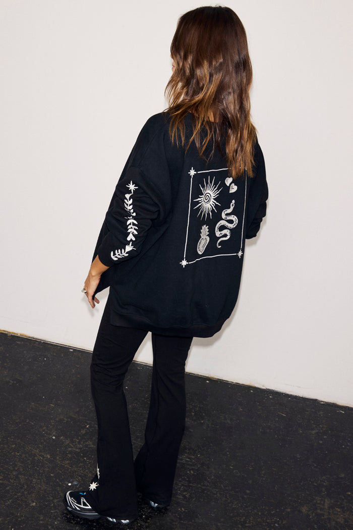 Black oversized sweatshirt with ecru sun and snake embroidery on the back and floral sleeve detailing.