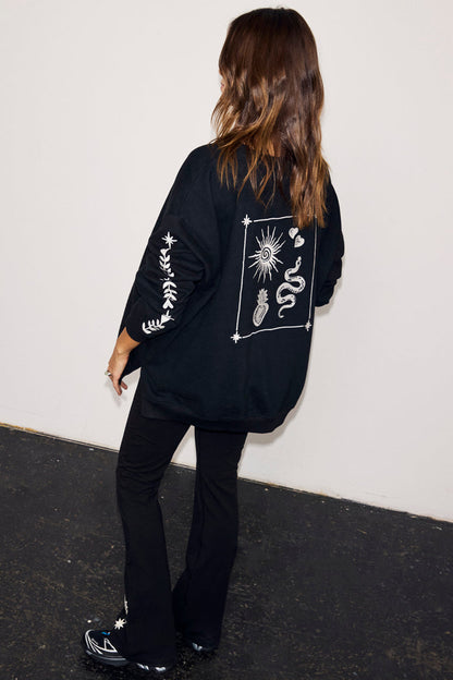 Black oversized sweatshirt with ecru sun and snake embroidery on the back and floral sleeve detailing.