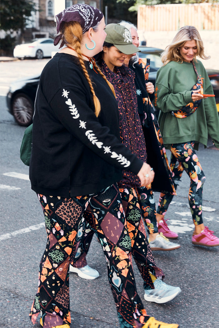 Black Sweatshirt with ecru sleeve motifs, styled in a London street scene highlighting inclusive sizing.
