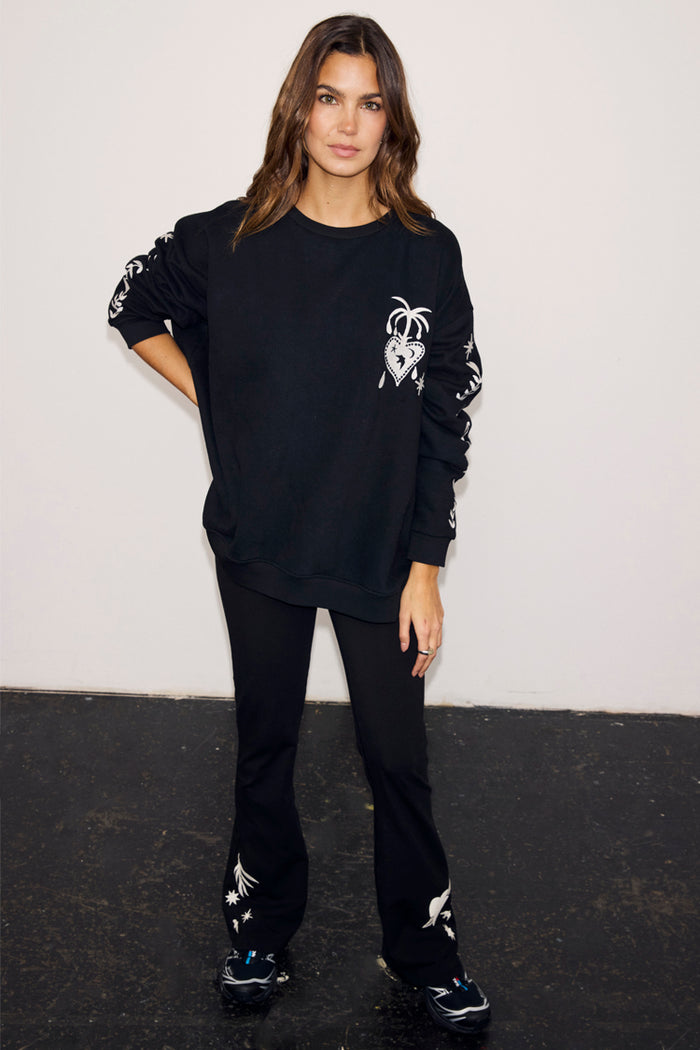 Black oversized sweatshirt with ecru signature motifs embroidered on the chest and sleeves, paired with matching trousers.