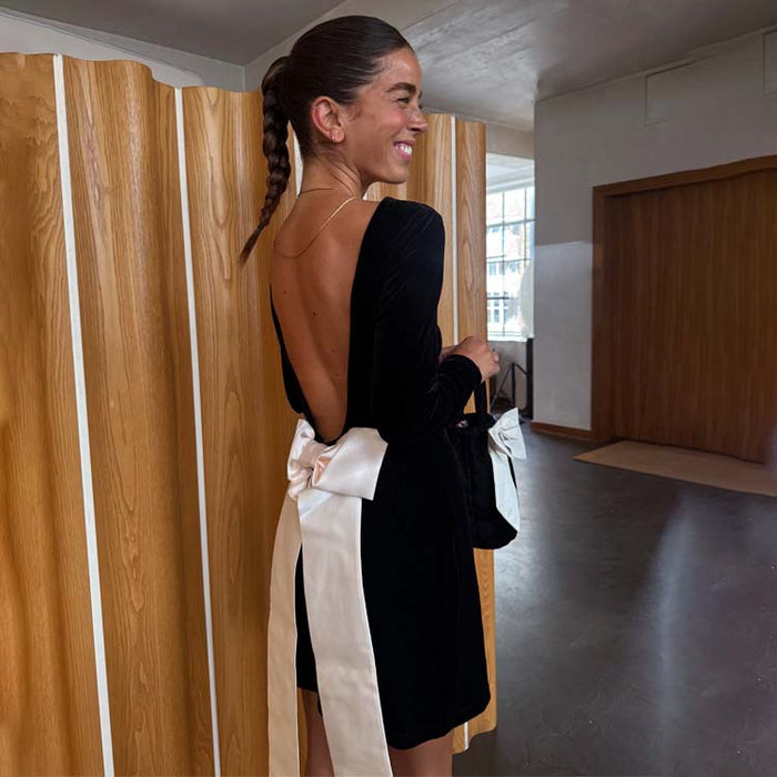 Black Velvet Bow Mini Dress with an open back and large cream detachable bow, designed in London.