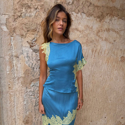 Blue and Lemon Kira Top with contrast lace and an asymmetric hem, worn as a co-ord against a stone wall.