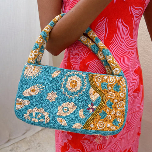 Blue and Yellow Morocco Beaded bag with hand-embellished glass beads and iconic NFD motifs, held by a model.