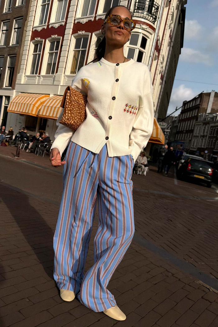 Blue Cotton Stripe Jogger with red pinstripes, paired with a white button-up cardigan for a London street style look.