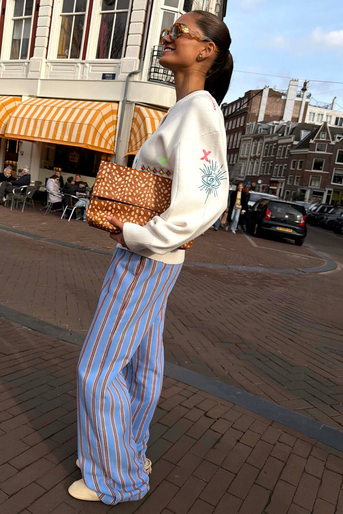 Blue Cotton Stripe Jogger with red pinstripes, styled with a cream embroidered sweater and leopard print clutch.