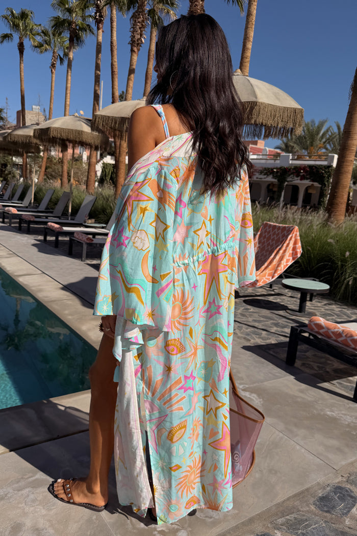 Blue Dreamer Maxi Kimono in light blue with palm and sun motifs, worn by a 5ft7 model in size M by a pool.