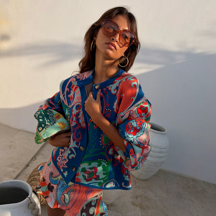 Blue Mari Cardigan in an orange and turquoise paisley knit, worn as a co-ord in a sunny outdoor setting.