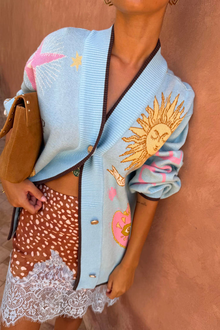 Blue Mystical Cardigan with sun and moon jacquard motifs, brown ribbed trims and gold buttons.